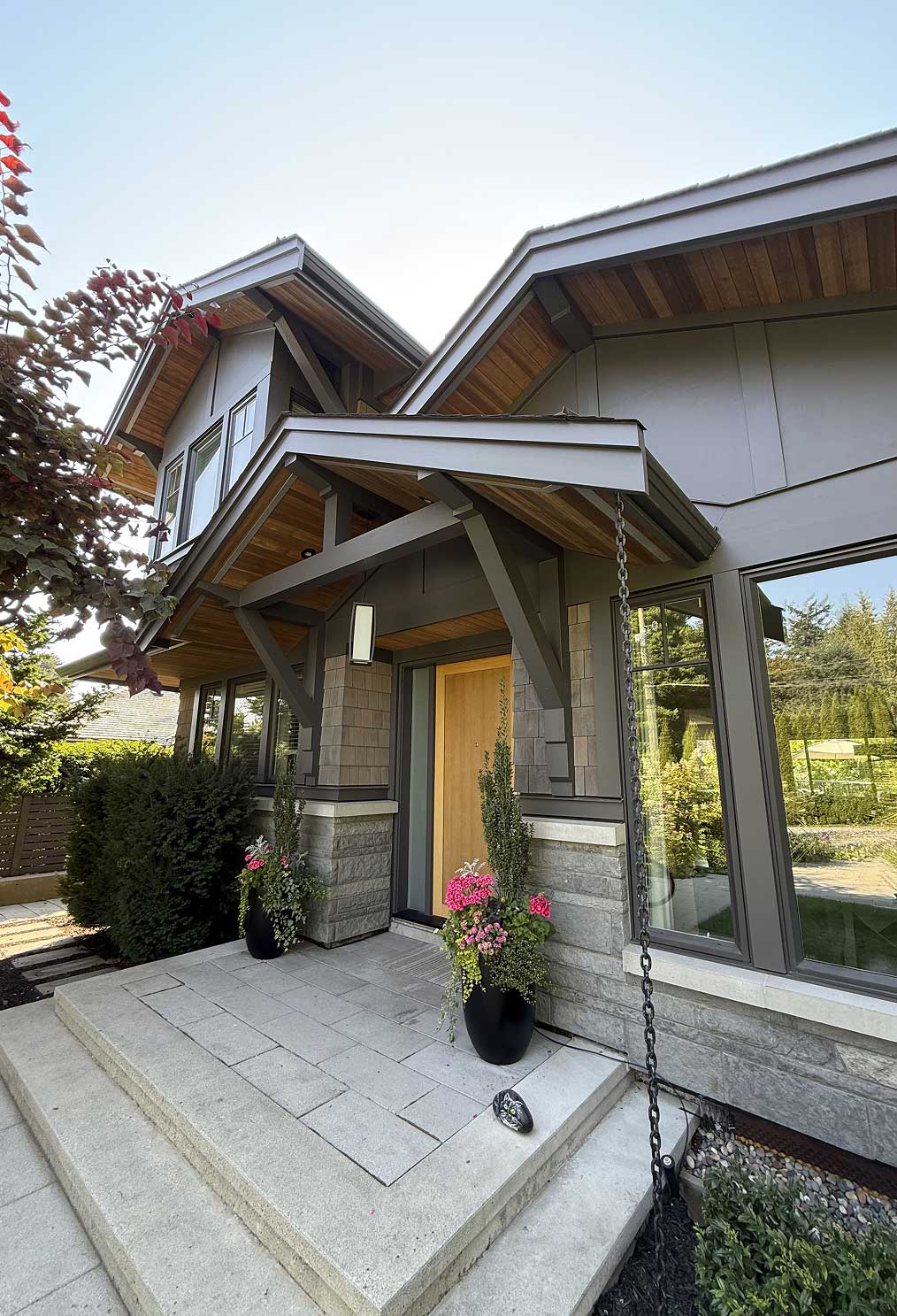 craftsman-entry-porch-exterior-paint-trim Craftsman entry porch with grey-green painted timber brackets, panel siding, and window trim under stained cedar soffits