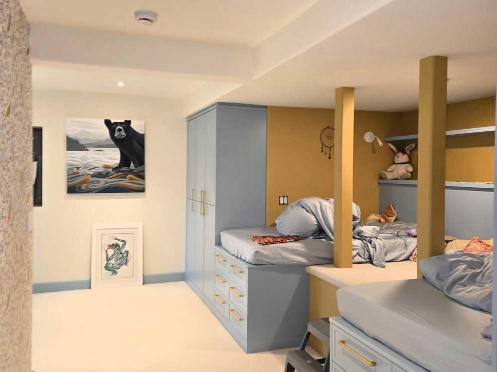Kids' bedroom with painted blue-grey built-in beds and cabinets, mustard yellow accent walls and posts, and matching blue baseboards